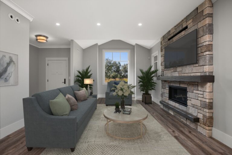 Cozy living room with gray sofa, multiple throw pillows, a glass-topped coffee table, and a stone fireplace.